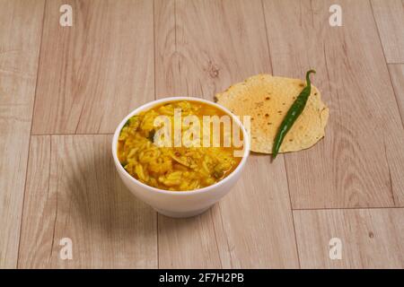 Dal khichadi or Khichdi Tasty Indian recipe served in bowl over moody background is made of toovar dal and rice combined with whole spices, onions, ga Stock Photo