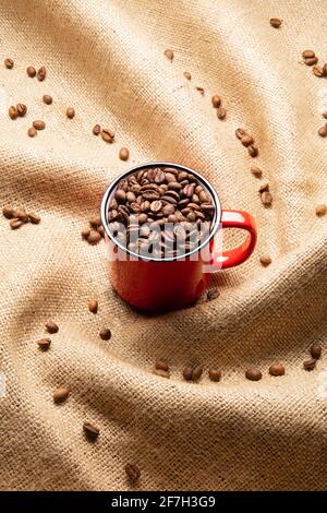 Red mug with coffee beans on twisted burlap background Stock Photo