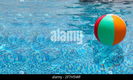 Beach ball in pool. Colorful inflatable ball floating in swimming pool. Stock Photo