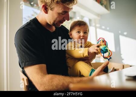Man spending quality time with his adorable child at home. Man on paternity leave at home taking care of his son. Stock Photo