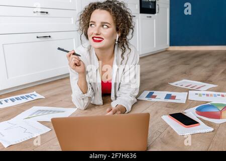 Successful business woman is using laptop, find an awesome idea for new project or presentation, smiling. Beautiful female freelancer or student lays Stock Photo