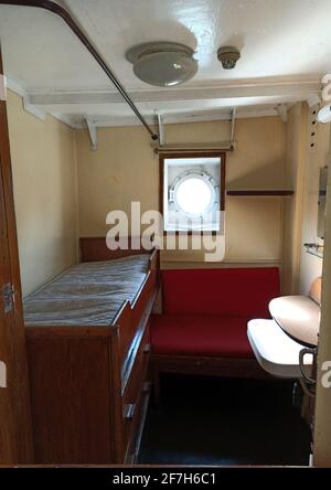 Gdansk, Poland - May 07, 2020: Cabin with congested sitting and sleeping area with round window inside the SS Soldek ship, part of the Polish Maritime Stock Photo