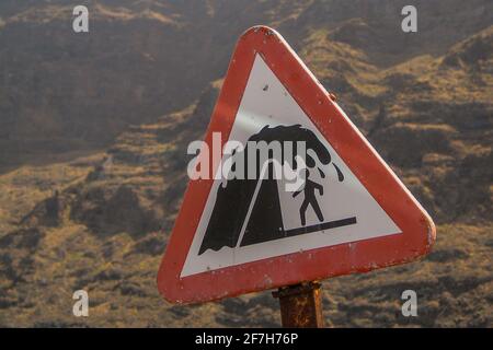 Warning traffic sign with danger of wave splashing over the wall on the beach. Interesting sign on the road next to the beach. Warning of a person get Stock Photo