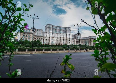 Seat of Romanian parliament, huge building in the centre of Bucharest, Romania on a cloudy summer day. View through the bushes. Epic view of Palatui P Stock Photo