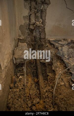 Broken water pipe in an apartment. Visible hole in the ground with tiles, old concrete and debris. Construction site while trying to remedy a water le Stock Photo