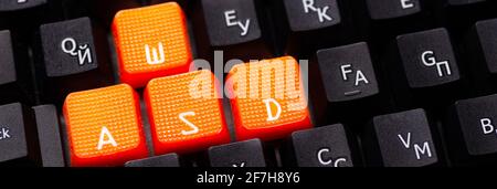 Orange arrow keys on a black keyboard, up, down, left, right buttons on a gaming computer keyboard. Stock Photo