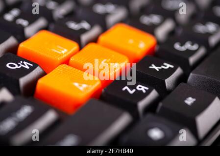 Close-up of orange arrow keys on a black keyboard, up, down, left, right buttons on a gaming computer keyboard. Stock Photo