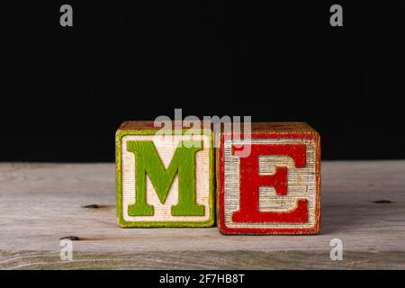 The word me spelled in vintage wooden blocks and black background. Stock Photo