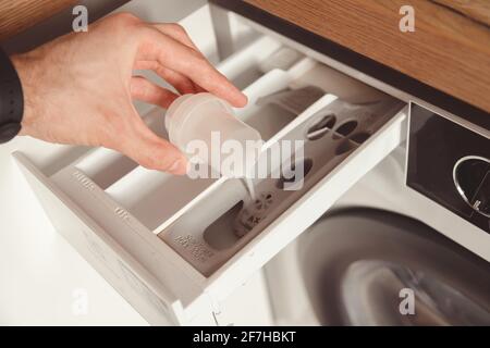 Man pouring the washing fabric conditioner into the washing machine to get more softer clothes Stock Photo