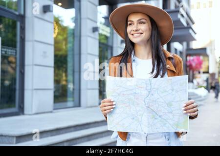 Happy attractive female in hat using map outdoor Stock Photo