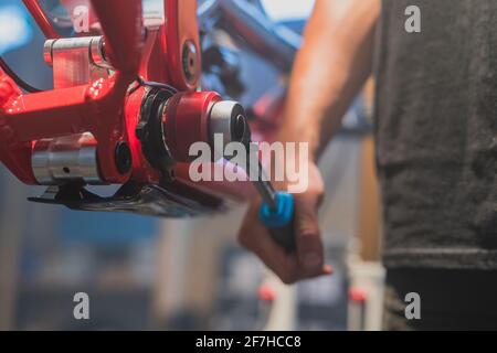 Mechanic or a person tightening a bottom bracket bearing on a downhill bicycle using a wrench. Stock Photo