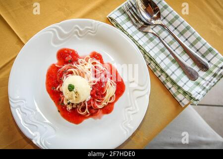 Spaghetti with a vanilla icecream cup and some herbs. Delicious but unconventional dessert on a table, photo taken from above. Stock Photo