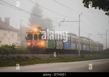 LJUBLJANA,SLOVENIA, 20.9.2018: Early vintage old commuter train in slovenia made by Pafawag in Poland in a foggy misty morning next to an adjacent roa Stock Photo