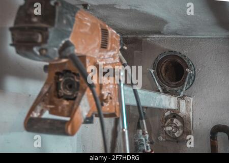 Machine for drilling holes in hthe concrete wall. Red professional drill for making holes in the walls. Back view with visible hole in the wall. Stock Photo