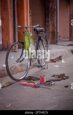 Roadside bicycle repair shop in India. Fix of a bicycle on a pedestrian walkway, tools lying on the ground. Nobody on the picture. Stock Photo