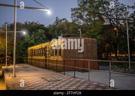 Old wooden carriages at night parked as an outdoor exhibition of railways in a park in the greek city of Kalamata. Outdoor railway museum in greece Stock Photo