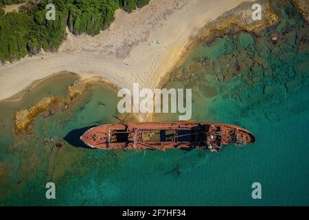 Aerial photo of Dimitrios shipwreck in  Gythio, Greece. A partially sunk rusty metal shipwreck decaying through time on a sandy beach on a sunny day. Stock Photo