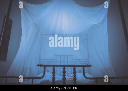 Frontal view of fancy nobel wooden double deluxe bed in Africa made out of wood poles. Mosquito net is hanging from above of the bed protecting the pe Stock Photo