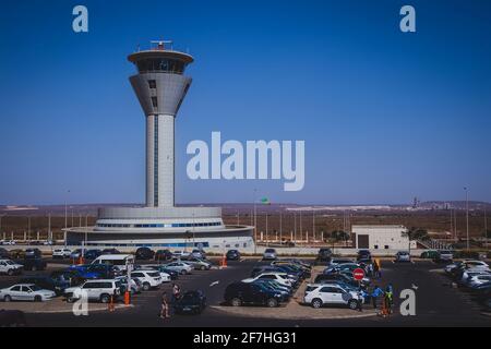 DAKAR, SENEGAL, FEBRUARY 22 2018: Control tower on the new Blaise Diagne airport in Dakar, Senegal on a sunny day. Some people, security guards and ca Stock Photo