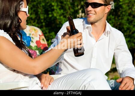 Couple in love drinking beer in summer in the garden and enjoy Stock Photo