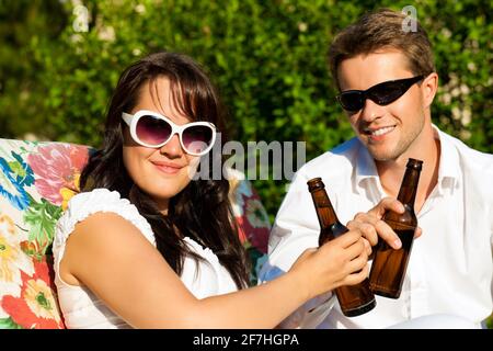Couple in love drinking beer in summer in the garden and enjoy Stock Photo