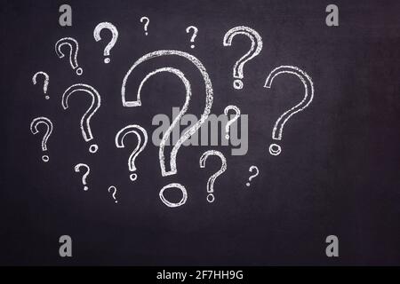Lots of question marks drawn in chalk on a black chalkboard. Stock Photo