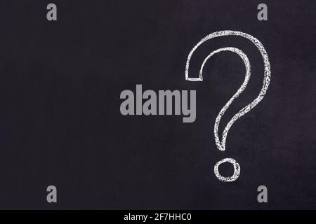 Question mark drawn in chalk on a black chalkboard. Stock Photo