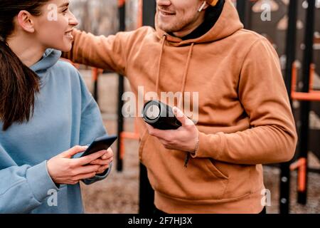 Young attractive sport woman and man in sportswear with wireless speaker listen to music at sports park Stock Photo