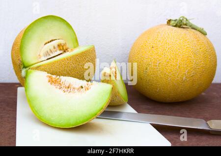 Still life where we see a pair of yellow melons (cantaloupes), one of them divided into portions allowing us to see the inside of the fruit Stock Photo