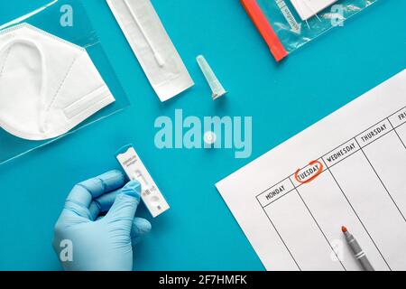 Express COVID-19 test schedule. Schnelltest means rapid corona test, and Selbsttest means self-test. Flat lay with hand in glove hold antigen covid Stock Photo