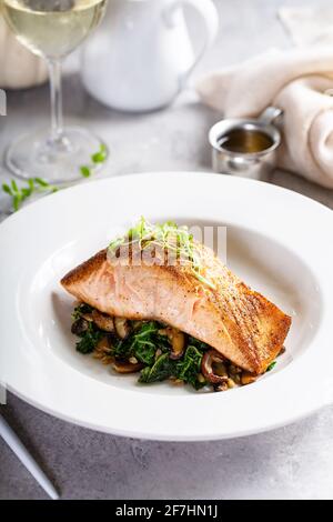 Salmon fillet served with sauteed greens and mushrooms Stock Photo