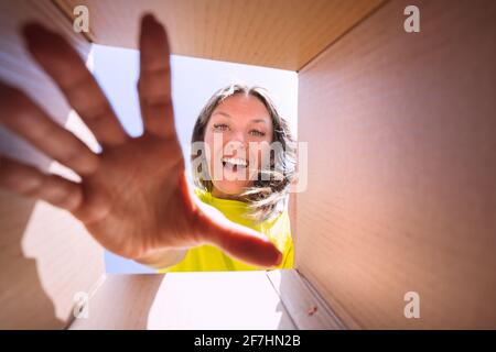 Happy satisfied woman unboxing delivery package. View from box.  Stock Photo