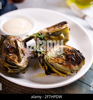 Grilled artichokes with a dipping sauce on a plate Stock Photo