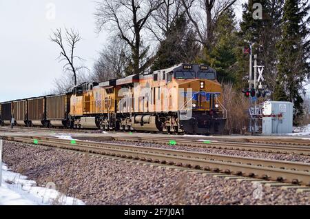 La Fox, Illinois, USA. Union Pacific Railroad locomotives lead an eastbound unit train through a rural road crossing on its journey to Chicago. Stock Photo