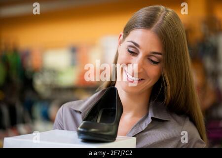 Happy woman shopping shoes in store; she is buying pumps Stock Photo