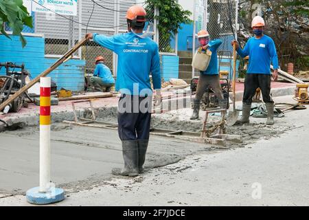 Road construction workers from Boracay Water in action, cementing the main road on Boracay Island, Aklan Province, Philippines during the pandemic. Stock Photo