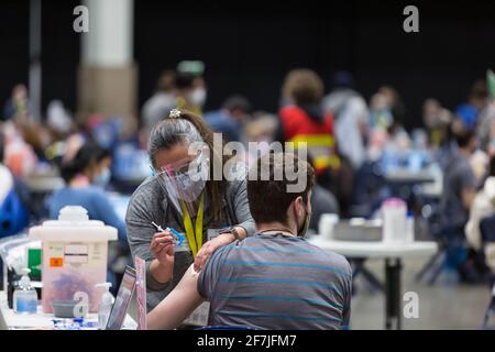 Seattle, Washington, USA. 7th April, 2021. A worker administers a dose of the Pfizer–BioNTech COVID-19 vaccine to a patient at the Lumen Field Event Center. The City of Seattle administered a record 7,615 doses of vaccine at the site on Wednesday. Credit: Paul Christian Gordon/Alamy Live News Stock Photo
