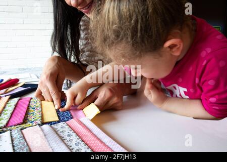 The little girl and her mother choose fabric for the new dress they will sew. selective focus fabrics Stock Photo