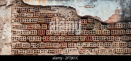 Brickwall, masonry with perforated bricks with round holes aged in row background, textured. Ceramic brickwork connected with cement, damaged exterior Stock Photo