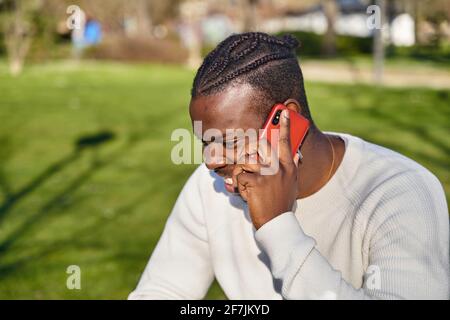Happy black man talking on smart phone sitting in a park on a sunny day. High quality photo Stock Photo