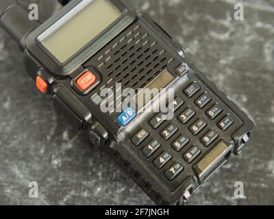 A portable black walkie-talkie with a display and keyboard on a dark background. Close-up Stock Photo