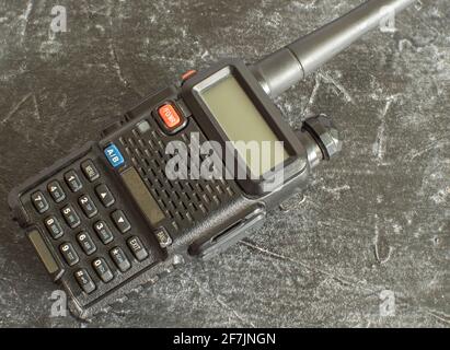 A black portable analog walkie-talkie on a dark concrete background. Close-up Stock Photo
