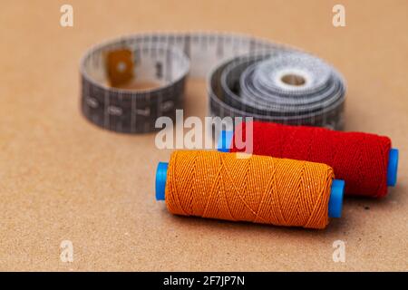Two thread spools and measuring tape on beige background Stock Photo
