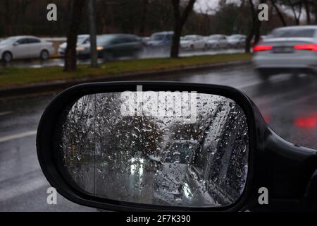 View from rear-view mirror in a rainy day with water drops Stock Photo