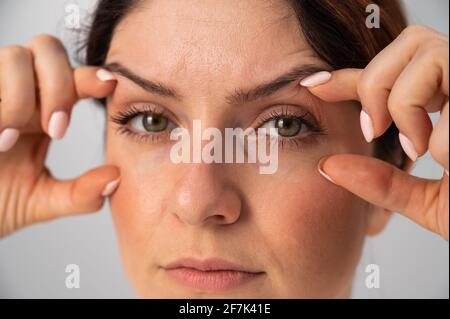 Close-up portrait of Caucasian middle-aged woman showing expression lines around eyes. Signs of aging on the face Stock Photo