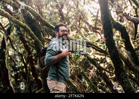 Standing traveler bearded man walk and enjoy the free nature forest in trekking activity - concept of handsome male people explore the woods with back Stock Photo