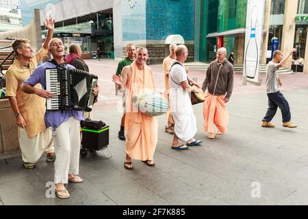 Hare Krishnas, some in orange robes, dancing and playing musical instruments in Aotea Square, Auckland, New Zealand Stock Photo
