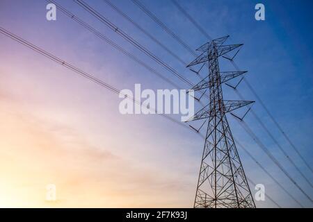 Silhouette of High voltage tower, electric power station for producing electricity at high voltage electricity poles at the sunset. Stock Photo