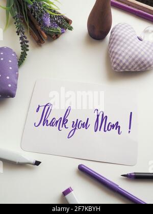 Thank you mother as brush lettering on a mothers day greeting card on a white table with decoration, happy Mothers Day Stock Photo