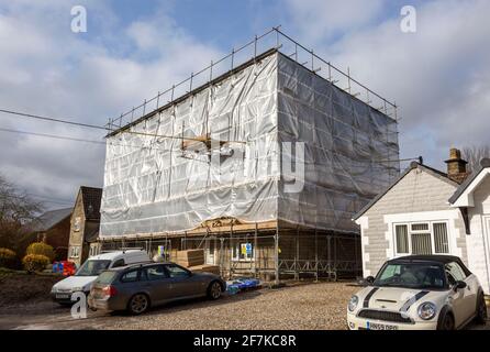 Scaffolding and protective screen around house undergoing major construction work, Cherhill, Wiltshire, England, UK Stock Photo